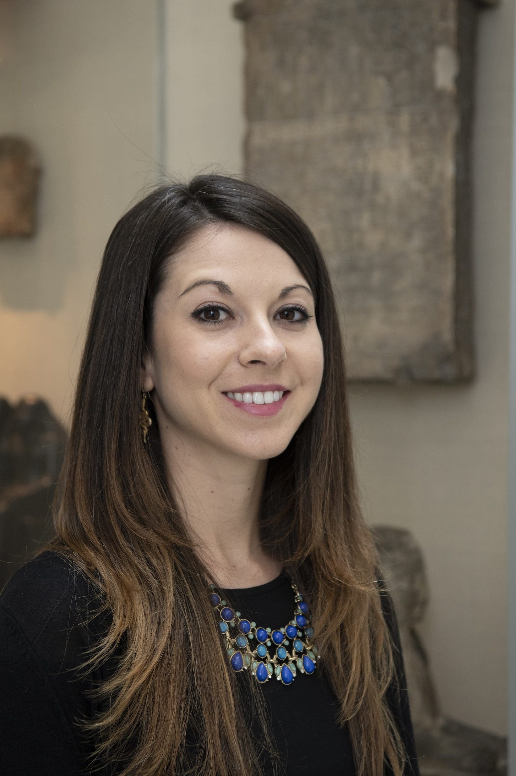 Headshot of Sr. Meg Swaney who is smiling and behind her is an Egyptian stela on display.